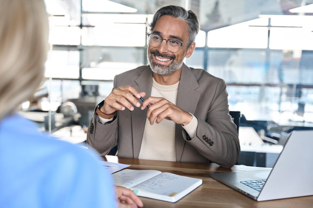 An employer sitting at a desk smiling talking to an employee