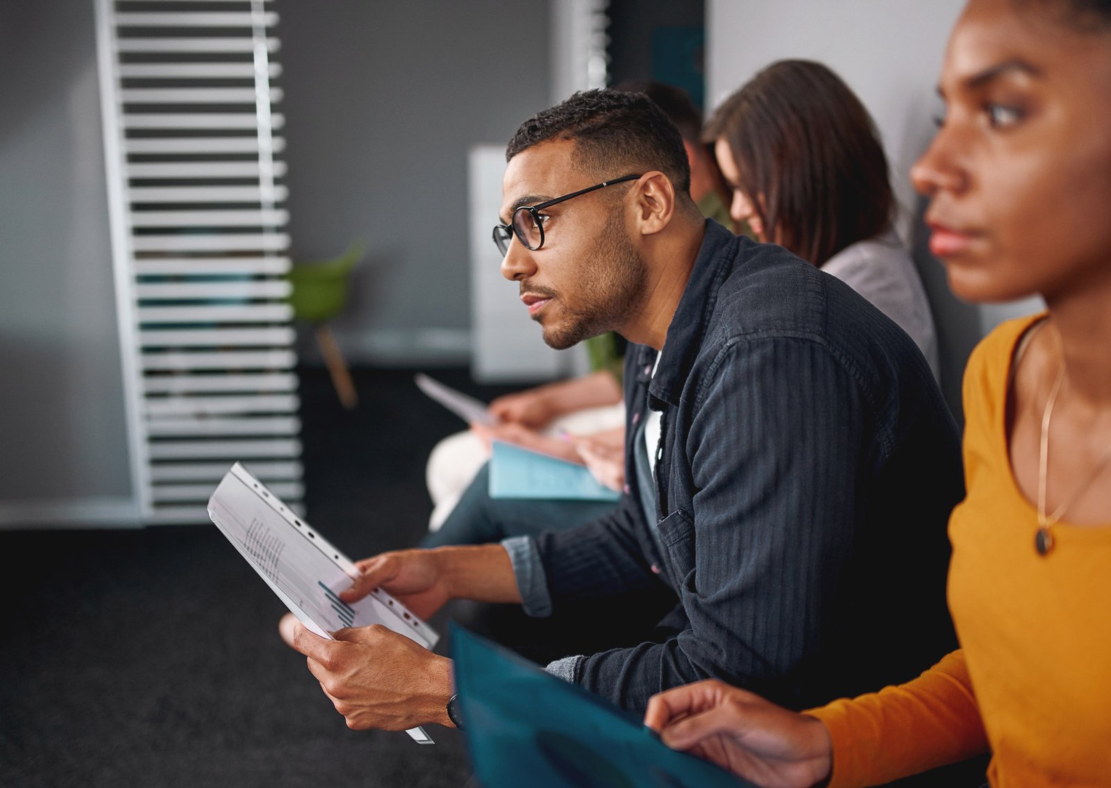 An employee sitting intently in a meeting holding paper