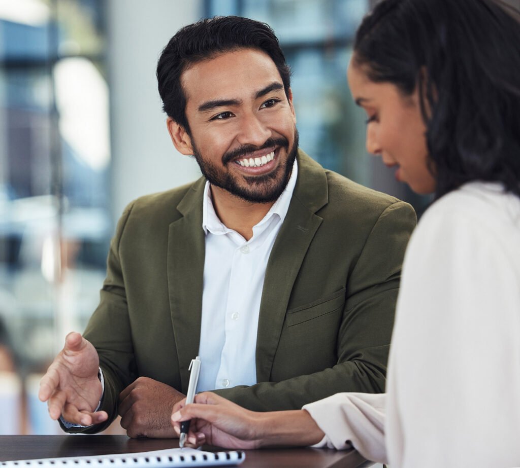 Two coworkers chatting and taking notes from a meeting