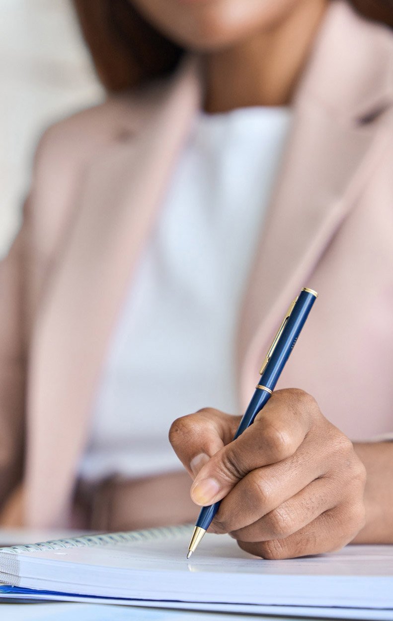 An employer taking notes on their paper with a laptop